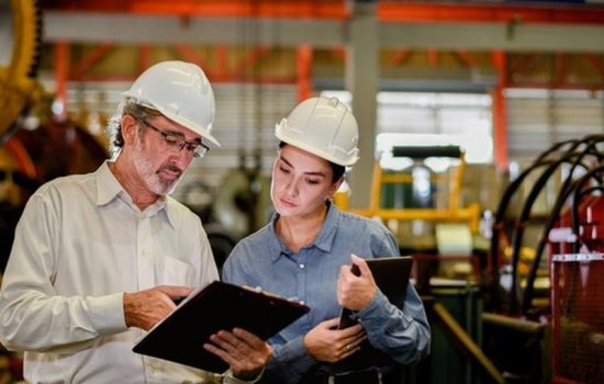 Responsable qualité et technicienne en casque consultant un document d'audit dans un atelier de production